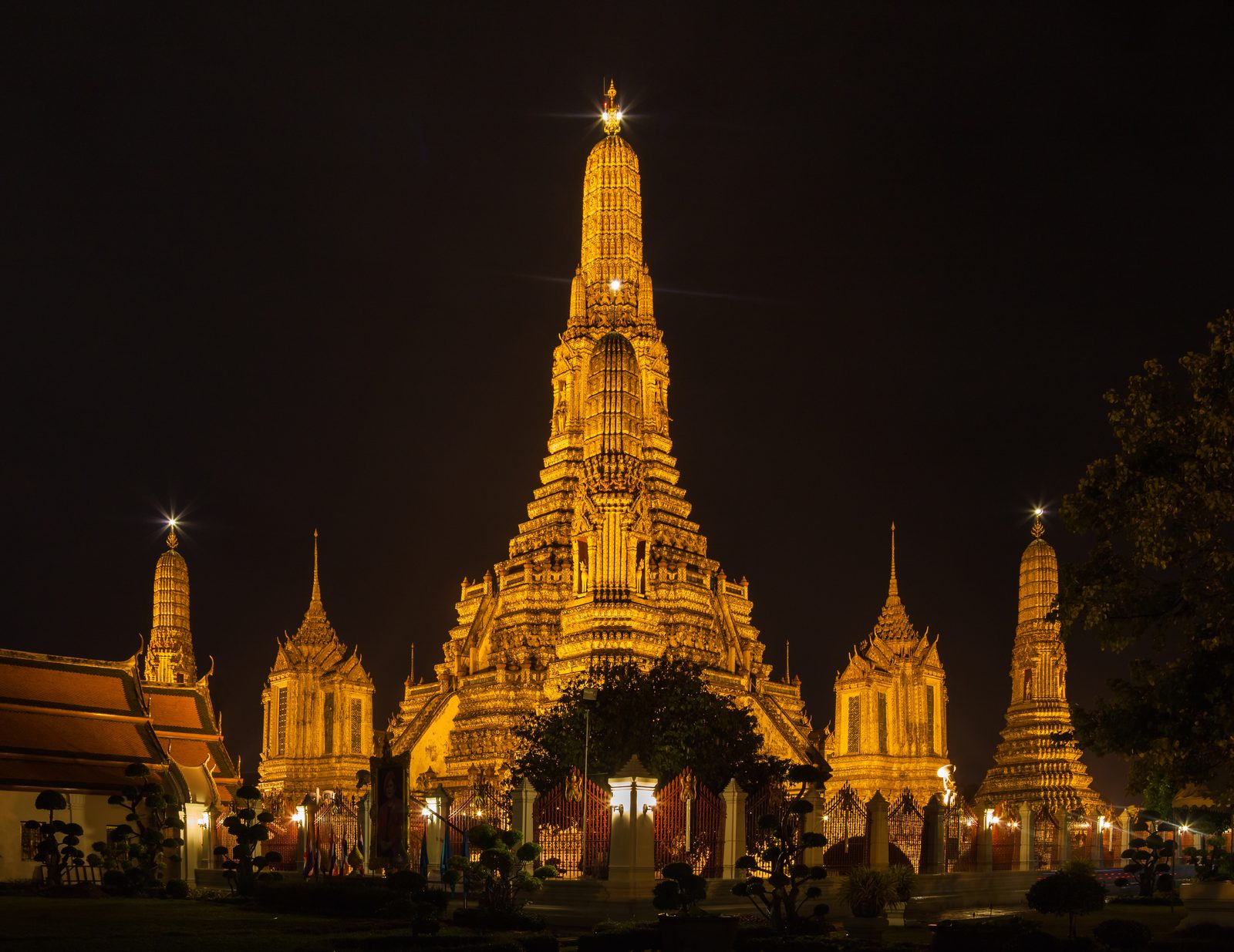 Wat Arun temple lit up at night beside the Chao Phraya River in Bangkok
